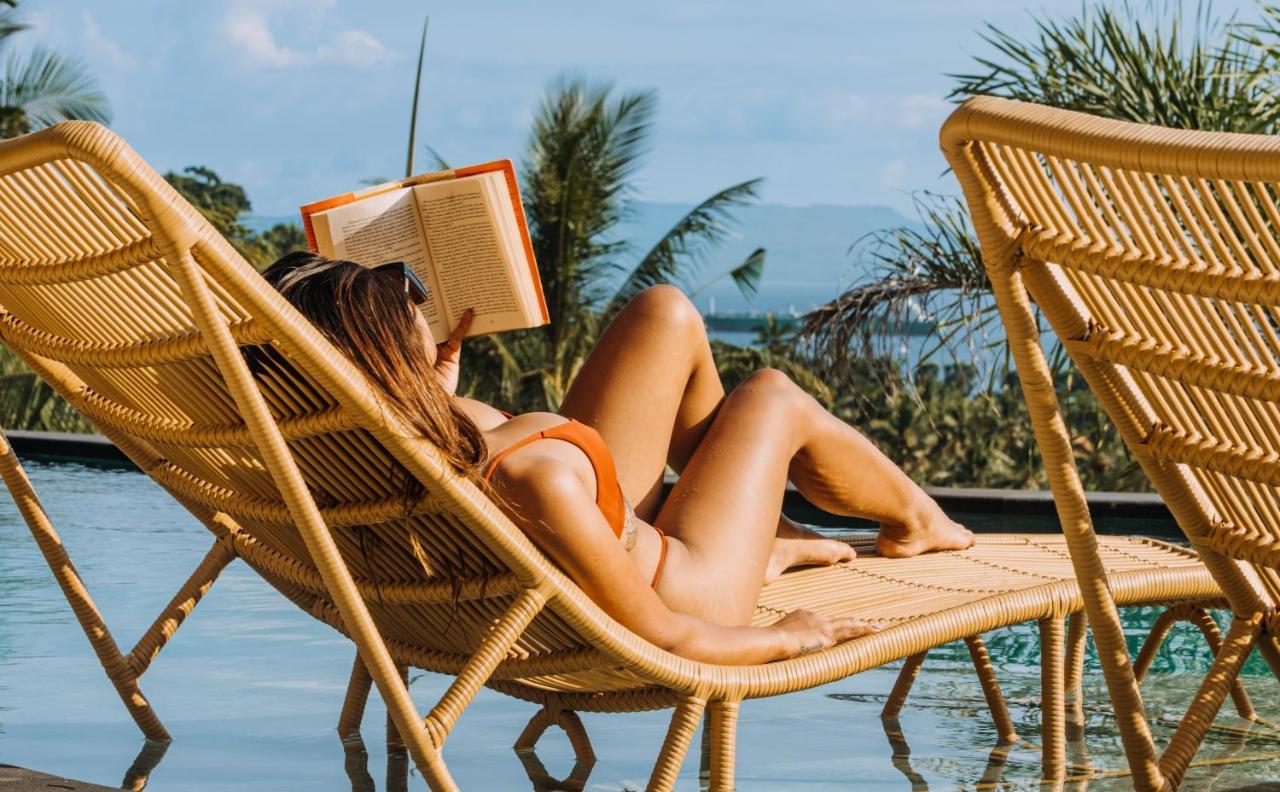 Neano Escape Hotel Manggis  ภายนอก รูปภาพ A woman reading a book on a beach